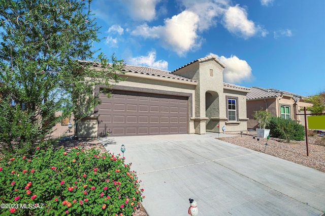 mediterranean / spanish home with a garage, driveway, a tile roof, and stucco siding