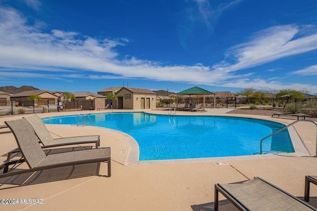 pool with a patio area, a residential view, and fence