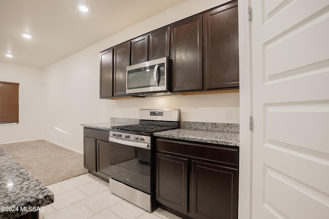 kitchen with light carpet, appliances with stainless steel finishes, light stone counters, dark brown cabinets, and recessed lighting