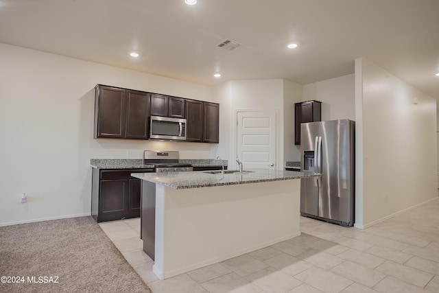 kitchen featuring light stone counters, stainless steel appliances, visible vents, a sink, and dark brown cabinets