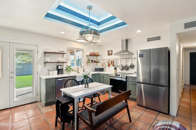 kitchen with visible vents, open shelves, stainless steel appliances, a raised ceiling, and wall chimney exhaust hood