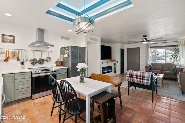 dining room featuring a glass covered fireplace, a raised ceiling, recessed lighting, and visible vents