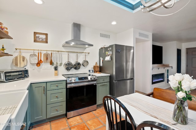 kitchen with visible vents, appliances with stainless steel finishes, wall chimney range hood, and green cabinetry