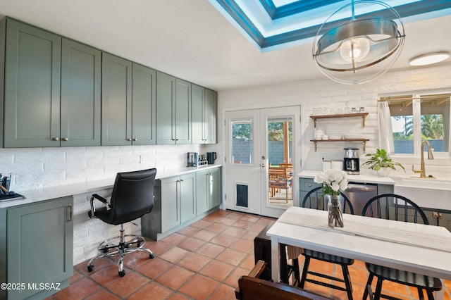 kitchen with decorative backsplash, built in study area, green cabinets, and light countertops