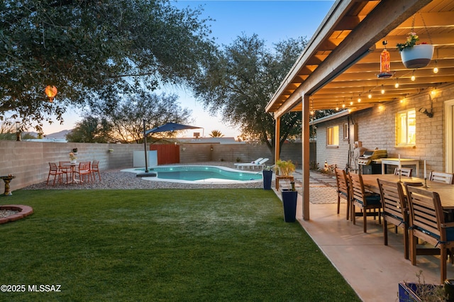 yard at dusk featuring outdoor dining area, a patio area, a fenced in pool, and a fenced backyard