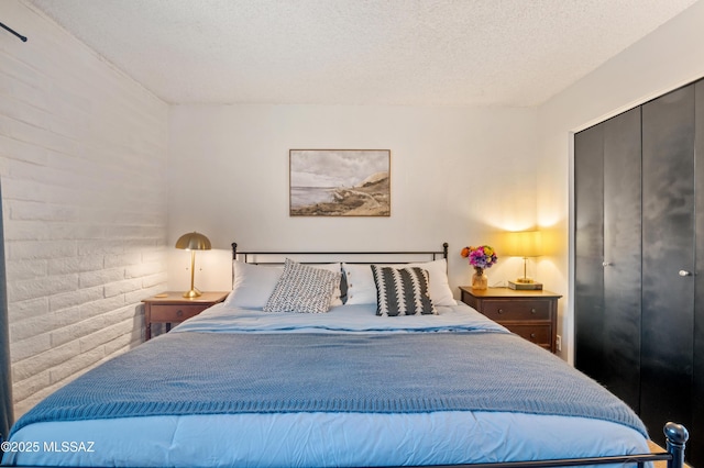 bedroom featuring brick wall and a textured ceiling