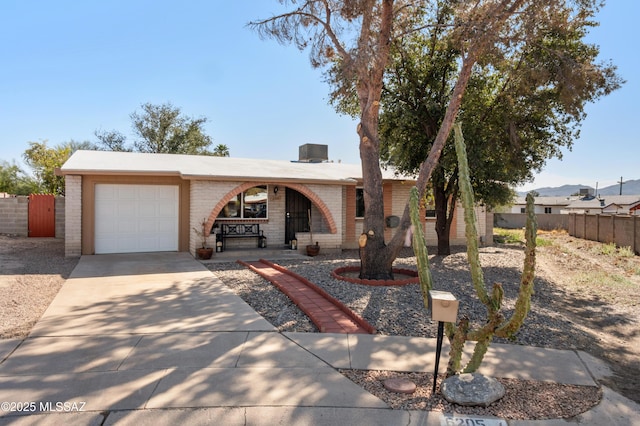 single story home with brick siding, concrete driveway, a garage, and fence