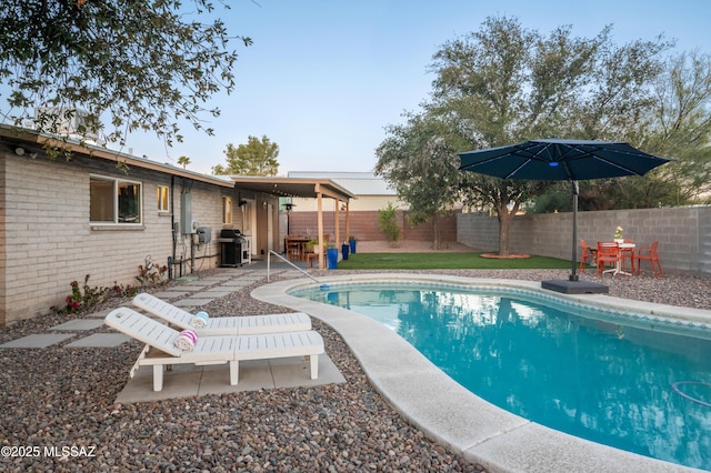 view of swimming pool with grilling area, a patio, a fenced in pool, and a fenced backyard