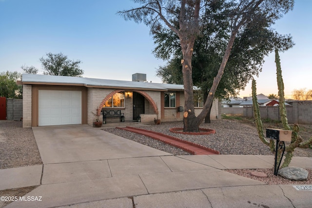 ranch-style home with brick siding, fence, covered porch, a garage, and driveway