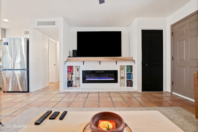 unfurnished living room featuring tile patterned floors, visible vents, and a glass covered fireplace