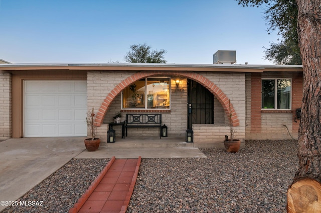 view of front of home with brick siding, a porch, concrete driveway, and a garage