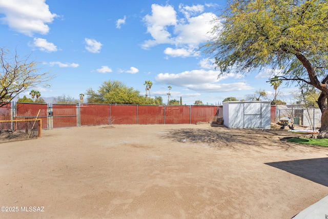 view of yard featuring a storage unit, an outbuilding, fence, and a gate