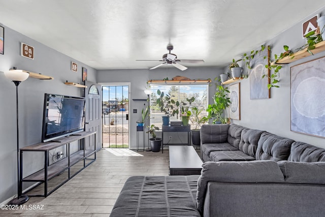 living area with baseboards, a ceiling fan, and wood finished floors