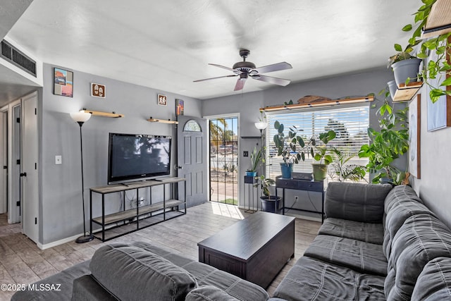 living area featuring a healthy amount of sunlight, wood finished floors, visible vents, and ceiling fan