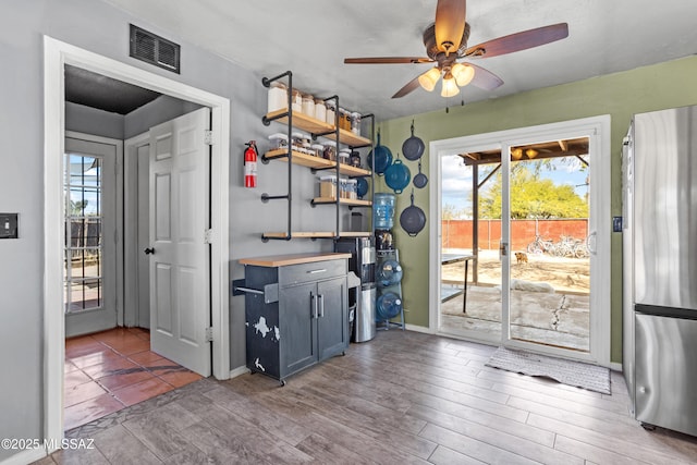 kitchen featuring wood finished floors, a ceiling fan, visible vents, baseboards, and freestanding refrigerator