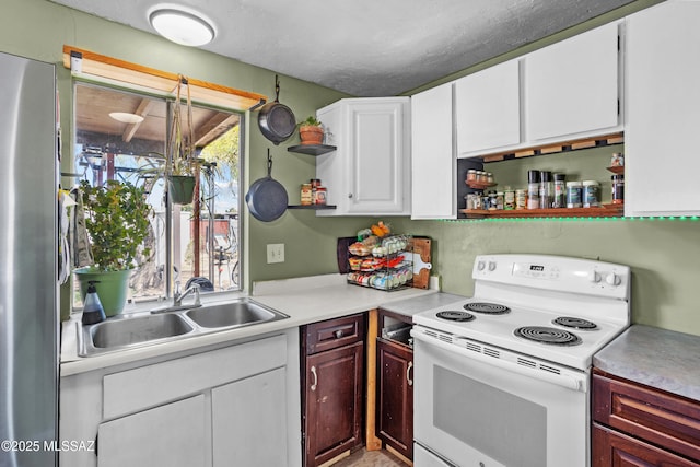 kitchen with open shelves, freestanding refrigerator, a sink, light countertops, and white electric range