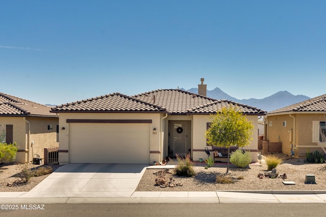 view of front facade with driveway, a tiled roof, a garage, and stucco siding