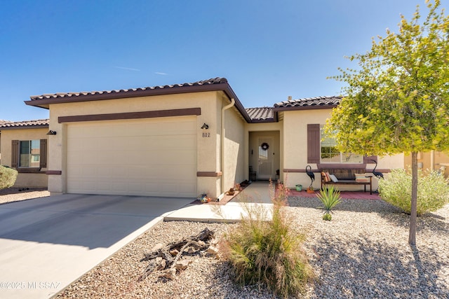 mediterranean / spanish house with concrete driveway, a tile roof, an attached garage, and stucco siding