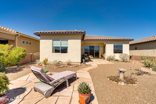 back of house with a patio area, a tiled roof, fence, and stucco siding