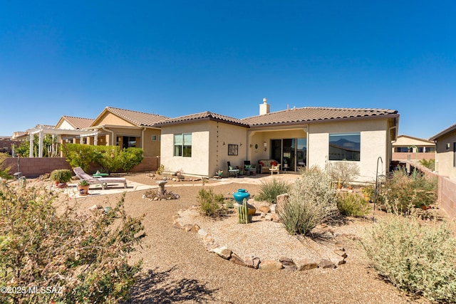 back of property with fence, a tiled roof, stucco siding, a chimney, and a patio area