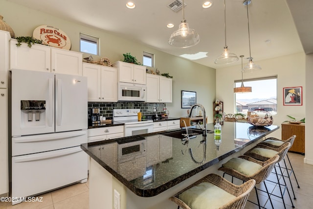 kitchen with white appliances, a sink, visible vents, white cabinetry, and tasteful backsplash