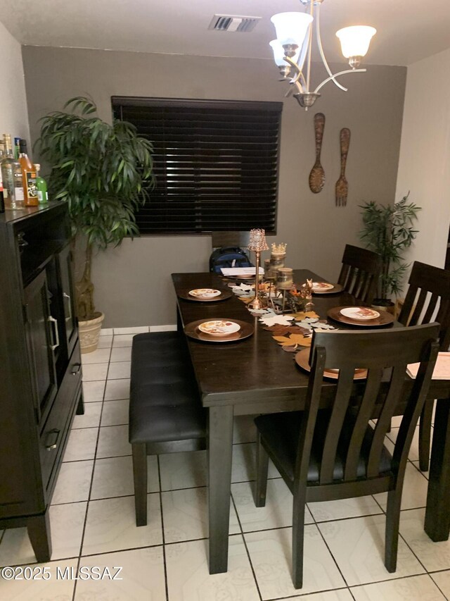 dining space featuring an inviting chandelier, light tile patterned flooring, baseboards, and visible vents