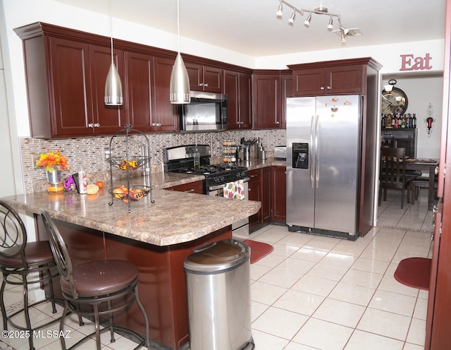 kitchen featuring light tile patterned floors, backsplash, appliances with stainless steel finishes, and a peninsula