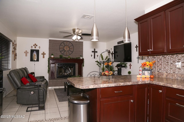 kitchen with a ceiling fan, a peninsula, a fireplace, open floor plan, and backsplash