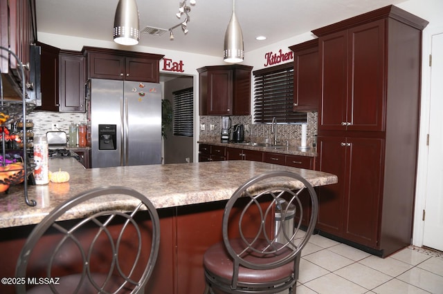 kitchen with a sink, a kitchen breakfast bar, stainless steel fridge, a peninsula, and light tile patterned floors