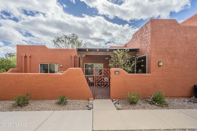 southwest-style home featuring a fenced front yard, a gate, and stucco siding