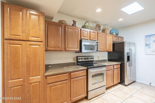 kitchen featuring light tile patterned floors, appliances with stainless steel finishes, brown cabinets, and recessed lighting