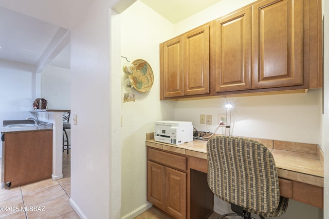 office space featuring a sink, light tile patterned flooring, built in study area, and baseboards