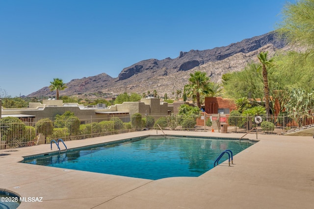 community pool with fence, a patio, and a mountain view