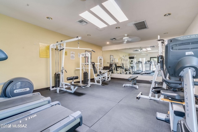 exercise room featuring ceiling fan, a skylight, visible vents, and baseboards