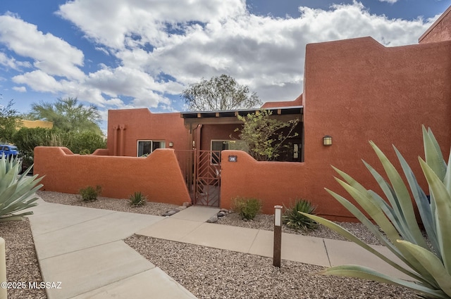 view of side of property with a fenced front yard, a gate, and stucco siding