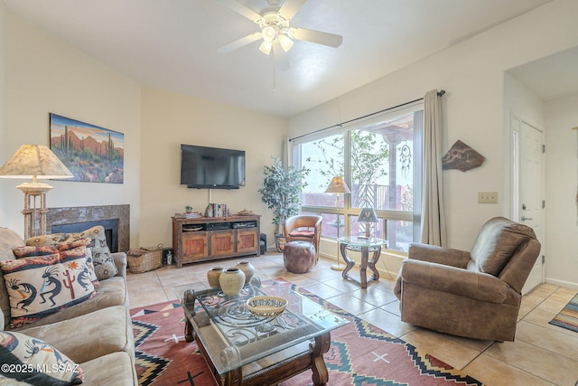 living room featuring light tile patterned floors, ceiling fan, a high end fireplace, and baseboards