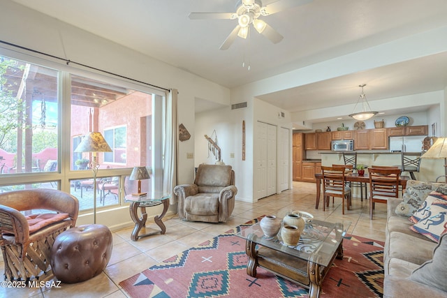 living area featuring light tile patterned floors, ceiling fan, visible vents, and baseboards