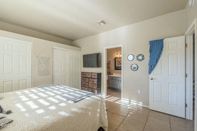 bedroom with light tile patterned floors, a closet, visible vents, and ensuite bathroom