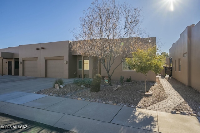 southwest-style home with a garage, central air condition unit, driveway, and stucco siding