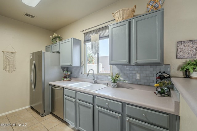 kitchen featuring appliances with stainless steel finishes, a sink, visible vents, and tasteful backsplash