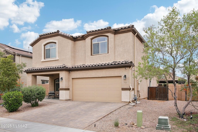 mediterranean / spanish-style home with a garage, fence, a tiled roof, decorative driveway, and stucco siding