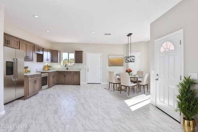 kitchen featuring visible vents, stainless steel fridge with ice dispenser, light countertops, marble finish floor, and a sink