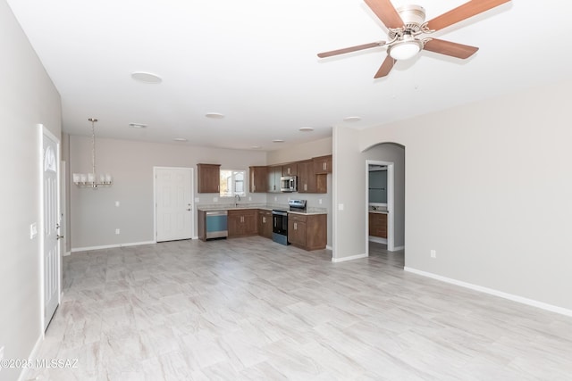 kitchen with stainless steel appliances, arched walkways, open floor plan, and light countertops