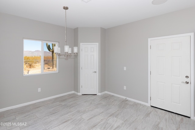 spare room featuring baseboards and a chandelier