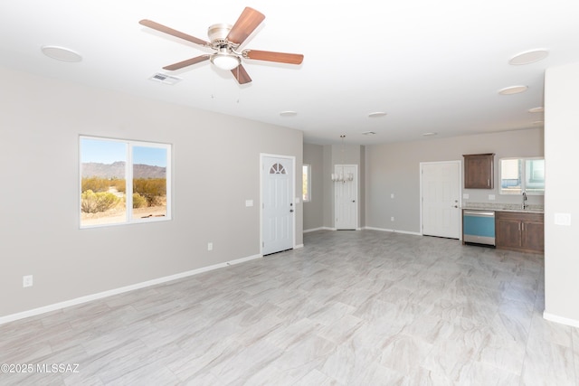 unfurnished living room featuring a sink, visible vents, baseboards, and a ceiling fan
