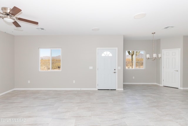 interior space with visible vents, ceiling fan with notable chandelier, baseboards, and a healthy amount of sunlight