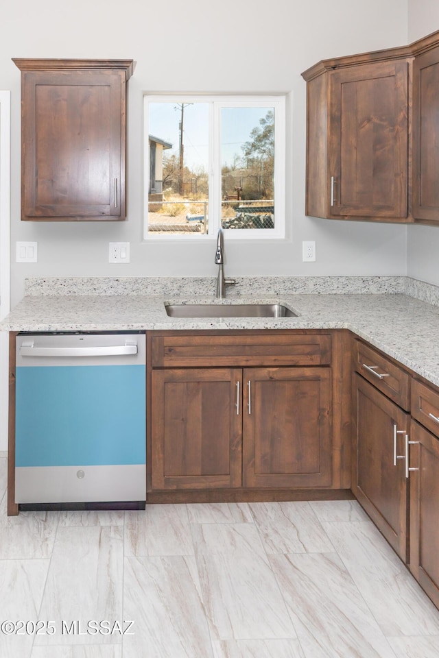 kitchen featuring light stone counters, dishwashing machine, marble finish floor, and a sink