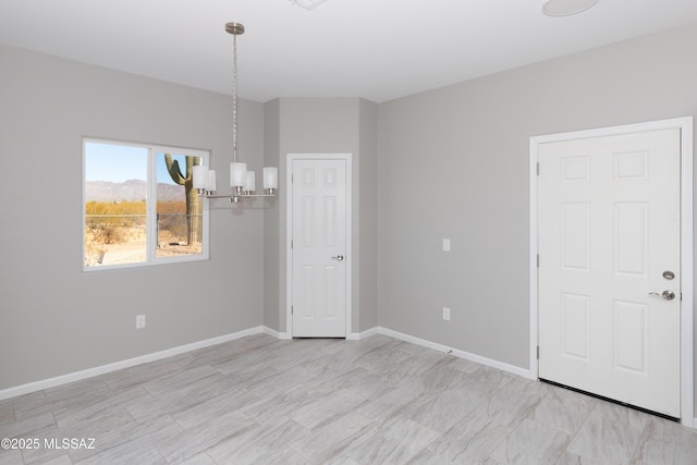 empty room with a notable chandelier and baseboards