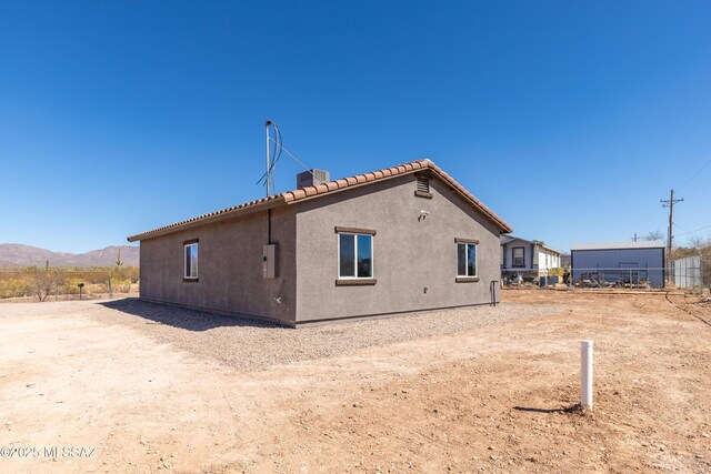 rear view of property with central air condition unit, a mountain view, stucco siding, and a tile roof