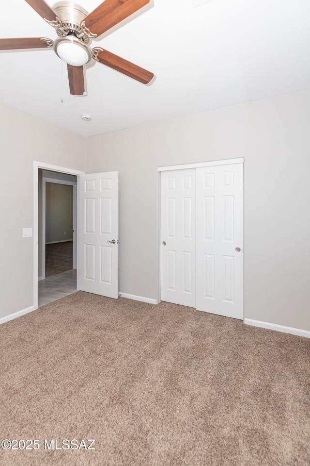 unfurnished bedroom featuring carpet floors, baseboards, a ceiling fan, and a closet